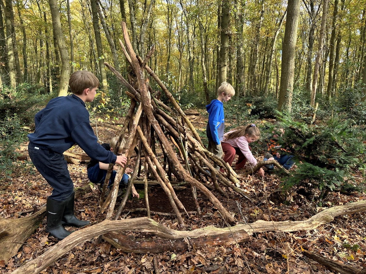Kinderen bouwen samen een hut van takken in het bos