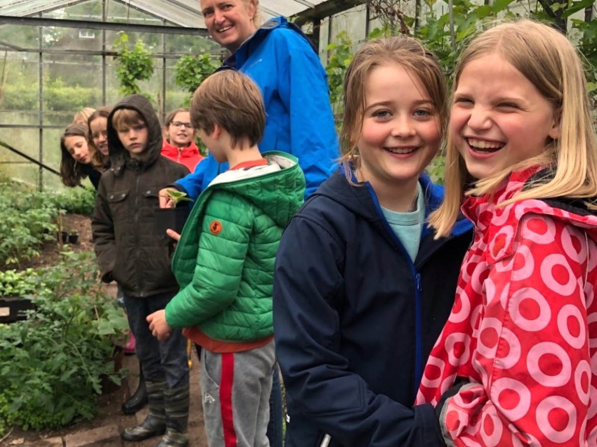 Lachende kinderen tijdens een tuinles in de kas