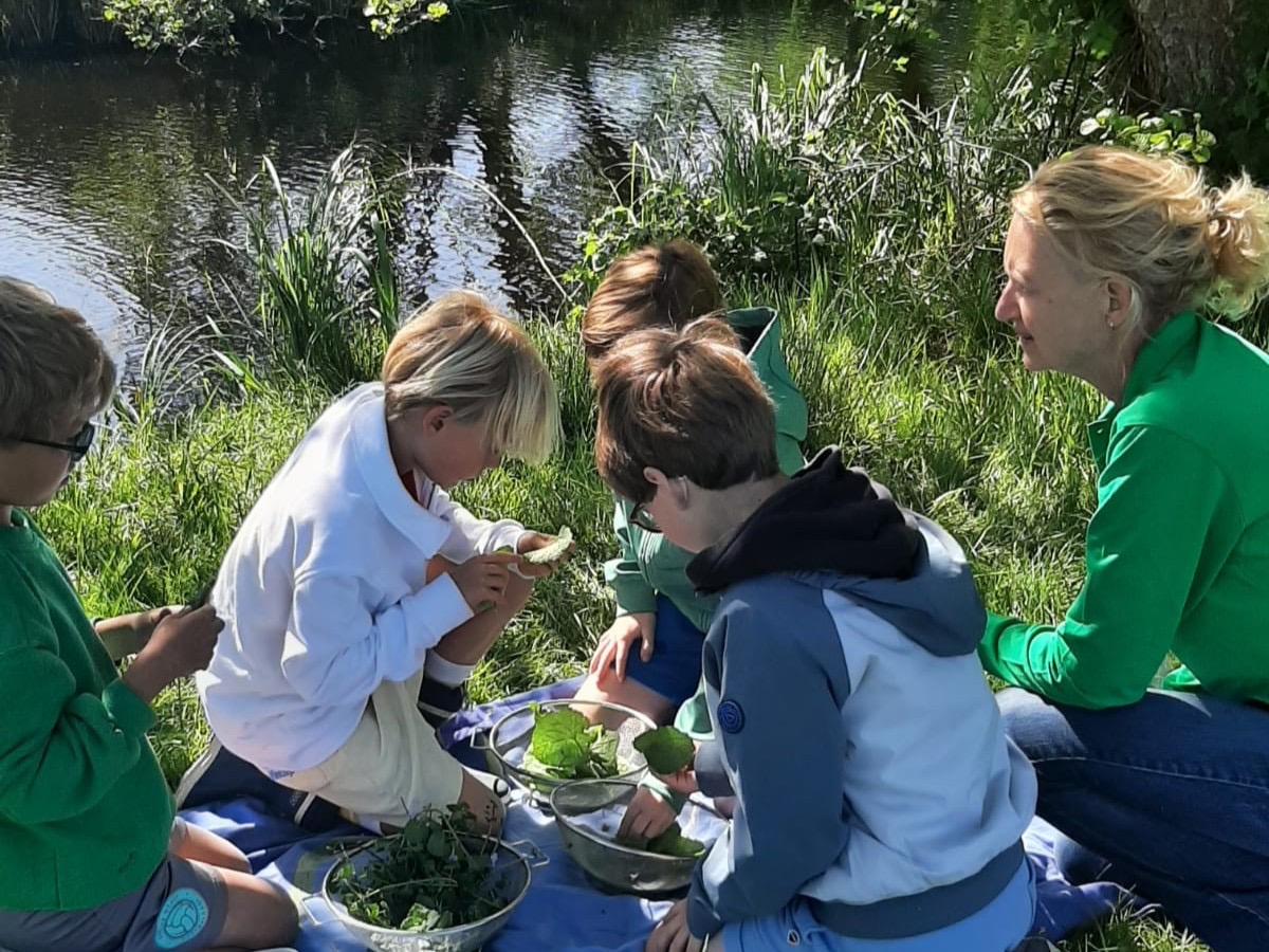 Kinderen maken samen iets met wildpluk bij het water